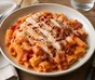 Rigatoni à la sauce tomate crémeuse avec poulet grillé, bacon croustillant et parmesan râpé