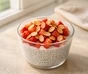 Pudding de chia au yaourt dans un verre, garni de fraises coupées et d'amandes effilées grillées